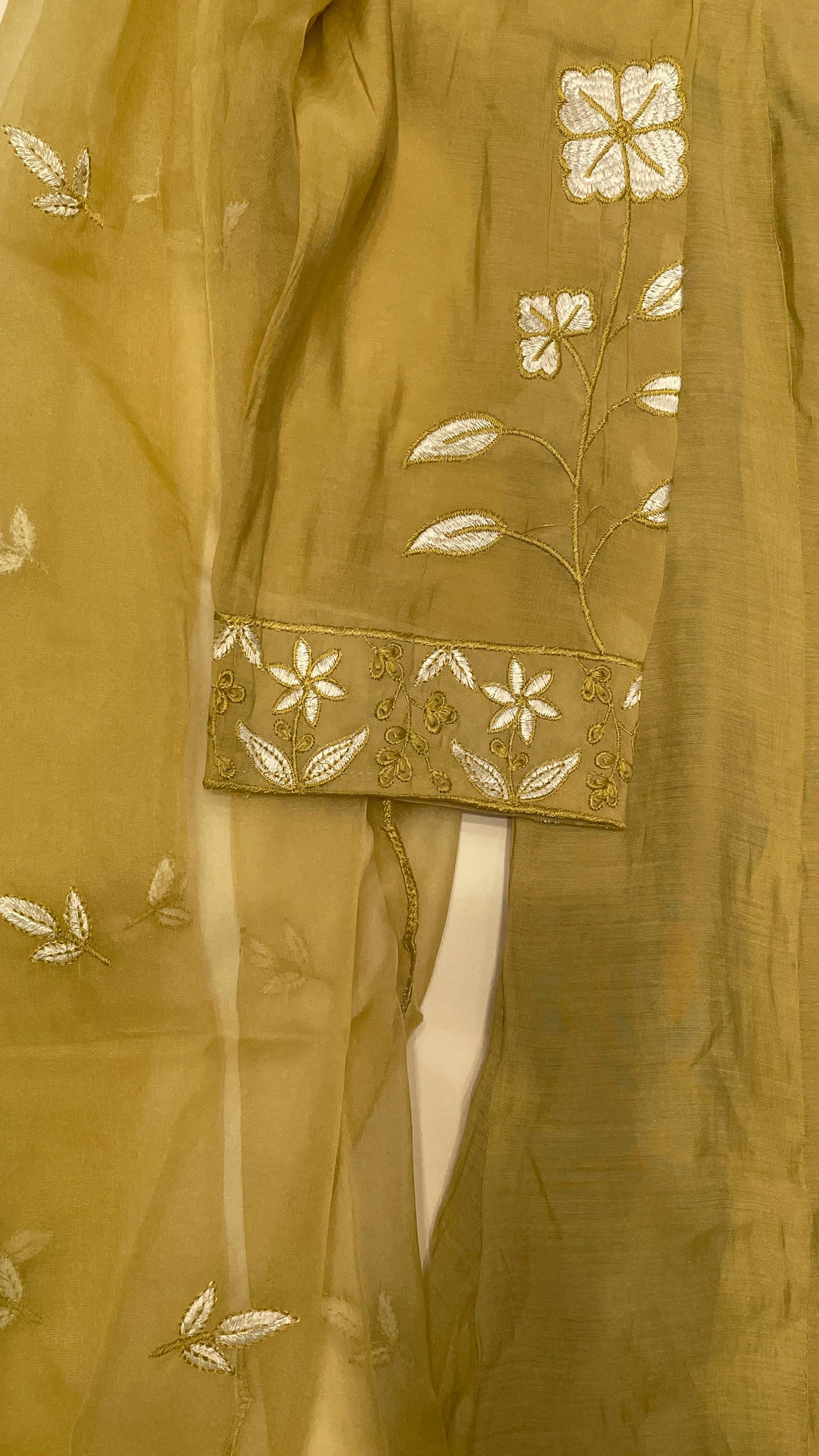 Close-up of a mustard yellow fabric with floral embroidery